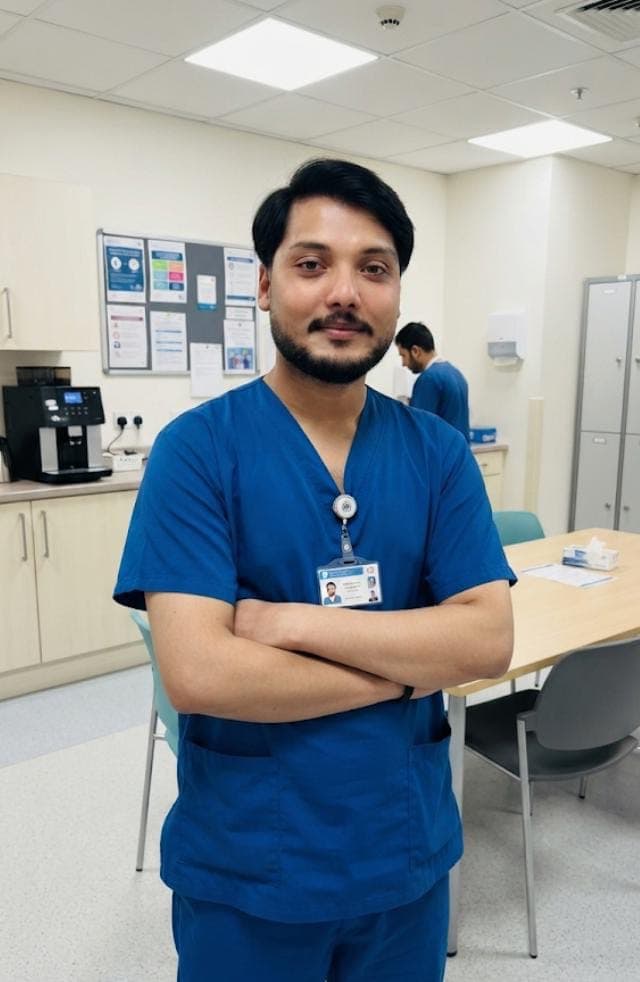 Caregiver in navy scrubs standing in a hospital staff room