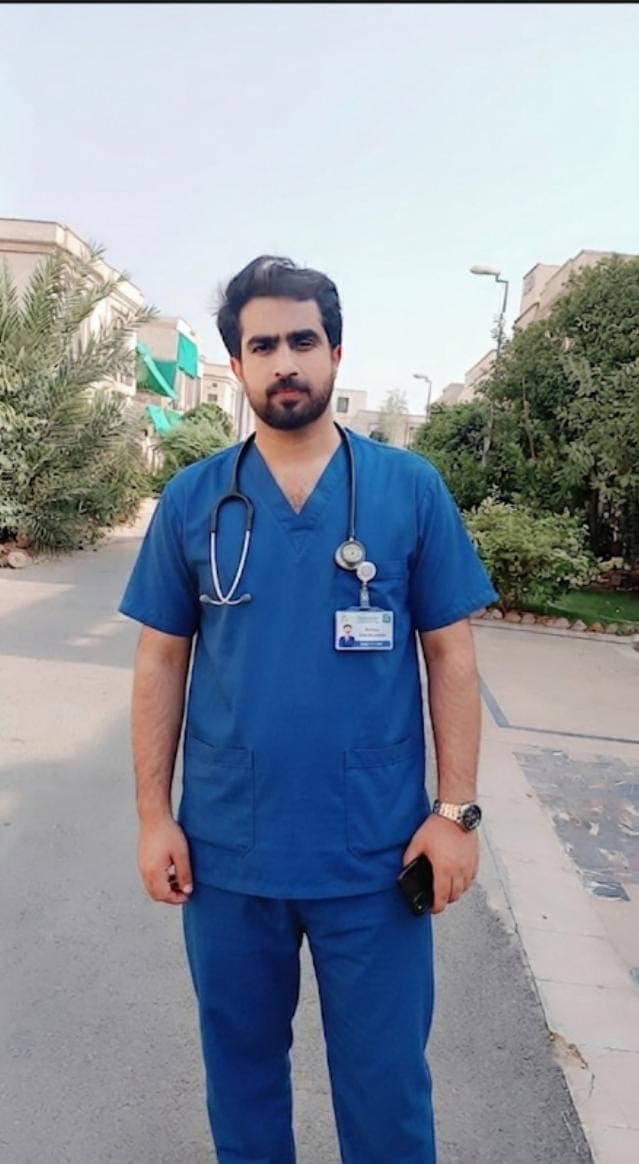 Caregiver in scrubs with a stethoscope, standing outdoors